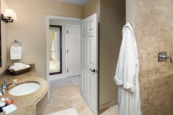 Sanderling Resort's modern hotel bathroom with a sink, towels, and a bathrobe hanging on the door.
