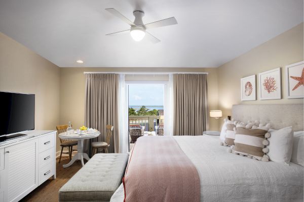 Sanderling Resort's neatly arranged hotel guest room with a bed, nightstands, TV, and a window with a balcony view.