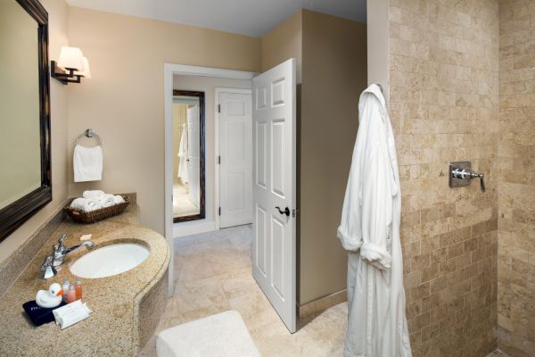 Sanderling Resort's modern guest bathroom with a sink, towels, robe, and a peek at the shower area.