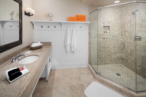 Modern bathroom with a shower, vanity sink, towels, and mirrors.