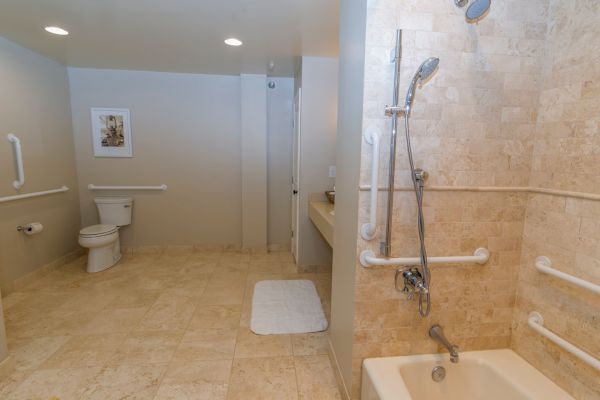 A bathroom with a shower, tub, toilet, and beige tiles.