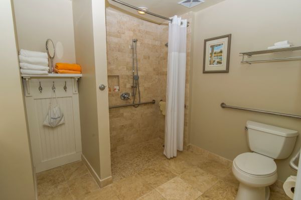 A clean bathroom with a shower, towels, and toilet is presented.