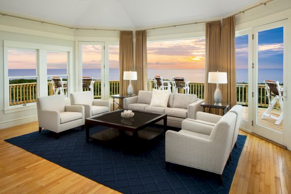Sanderling Resort's Caffey Vacation Home with an elegant living room with sofas, chairs, lamps, a coffee table, and a sea view during sunrise.